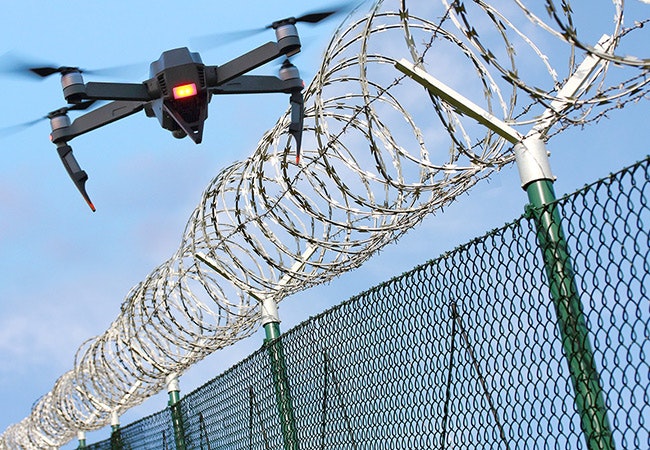 drone flying over barbed wire fence